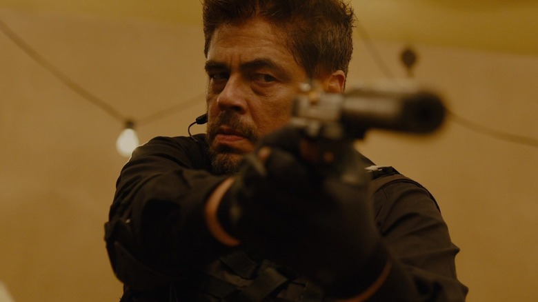 Alejandro Gillick (Benicio del Toro) care vizează un pistol tăcut în Sicario