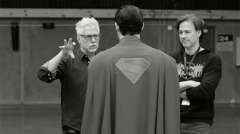 Regizorul James Gunn, vedeta David Corenswet și un alt membru al echipajului care vorbește împreună într-o scenă încă de la Superman