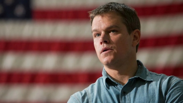 Matt Damon se află în fața unui steag al Statelor Unite ca Steve Butler în pământul promis
