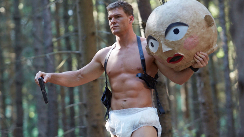 Alan Ritchson ca agent Carver care se plimbă printr -o pădure purtând un scutec în Dark Web Cicada 3301