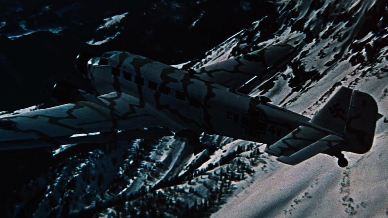 Un avion care zboară peste munții înzăpezi noaptea în locul în care Eagles îndrăznește