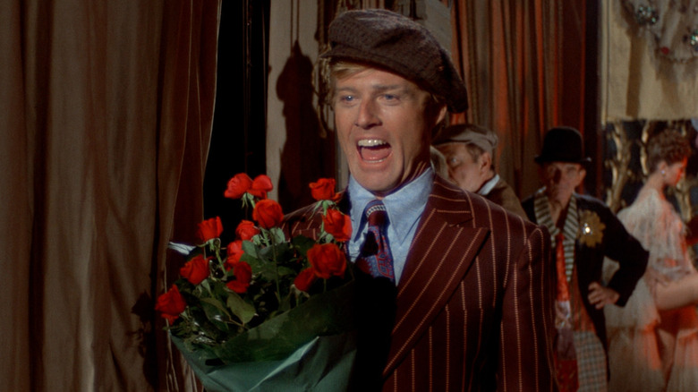 Robert Redford ca Johnny Hooker arătând încântat de flori în culise în înțepătură