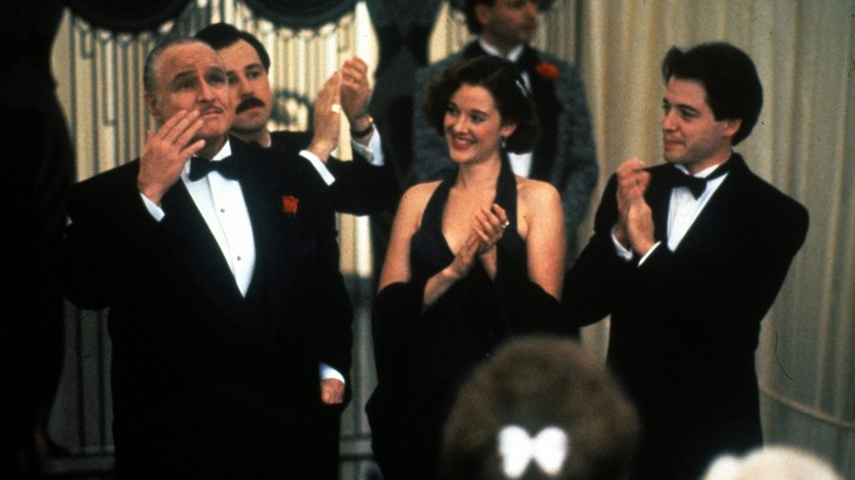 Marlon Brando ca Carmine Sabatini, Penelope Ann Miller în rolul lui Tina Sabatini și Matthew Broderick în timp ce Clark Kellogg sărbătoresc în The Freshman