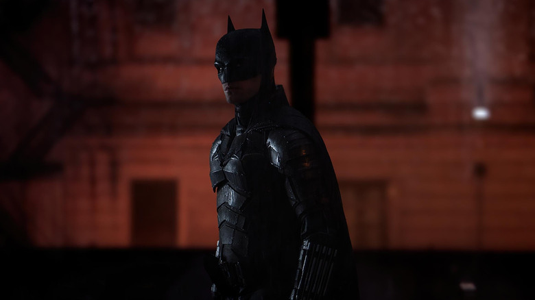 Robert Pattinson în timp ce Batman s -a înmuiat în ploaie stând pe străzile din Gotham din Batman