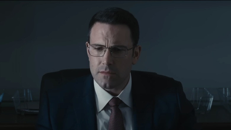 Christian Wolff al lui Ben Affleck este văzut stând pe un fundal gri simplu în contabil