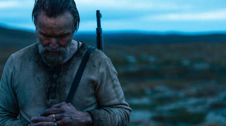 Aatami stând pe un câmp la amurg cu o pușcă pe spate în Sisu