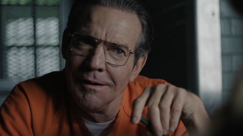 Keith Hunter Jesperson al lui Dennis Quaid zâmbește în timp ce purta un costum de sărituri din închisoare în fața fericită