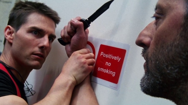 Ethan Hunt îl apucă pe Krieger de încheietura mâinii în timp ce ține un cuțit în misiune: imposibil