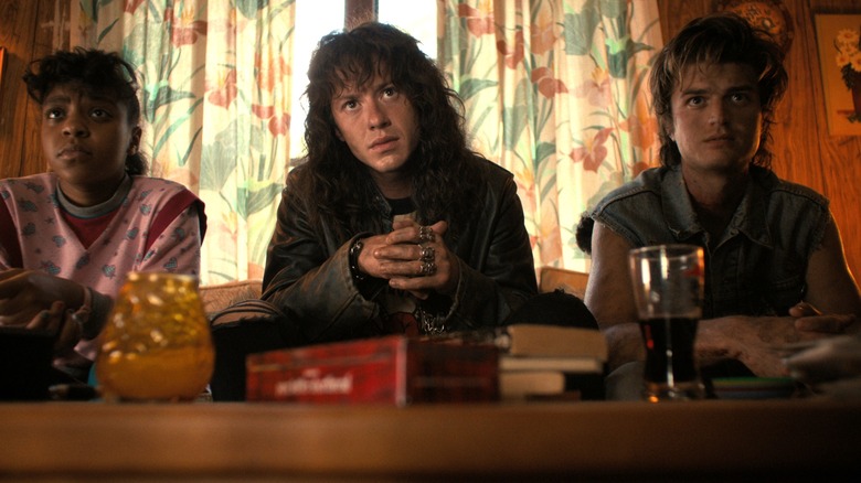 Erica, Eddie și Steve stând pe o canapea în Stranger Things Sezonul 4