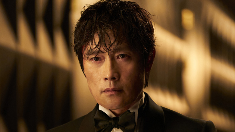 Bărbatul din față în costum fără ca masca lui să se uite înainte în jocul de calmar