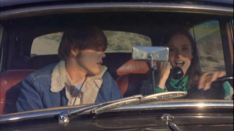 Sam în scaunul din față al unei mașini în timp ce Paula vorbește la telefon în Grand Theft Auto