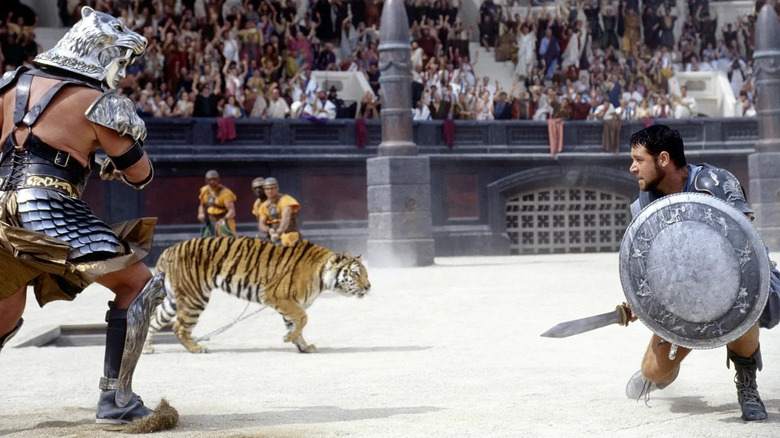 Maximus (Russell Crowe) luptând cu un gladiator și un tigru în arena din Gladiator