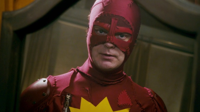 Rainn Wilson ca Frank Darbo în costumul său Crimson Bolt privind în oglindă în super