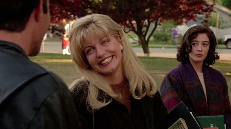 Sheryl Lee în rolul lui Laura Palmer zâmbind înfiorător cu Moira Kelly ca Donna Hayward în fundal în Twin Peaks: Fire Walk With Me