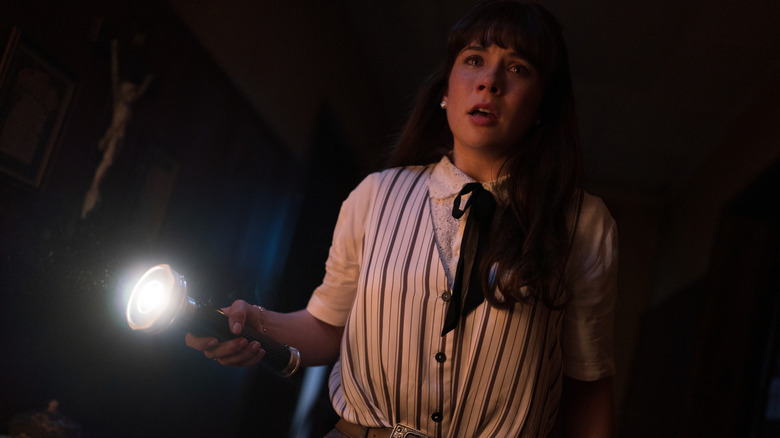 Judy investighează o mansardă întunecată cu o lanternă în Conjuring: Ultimele rituri