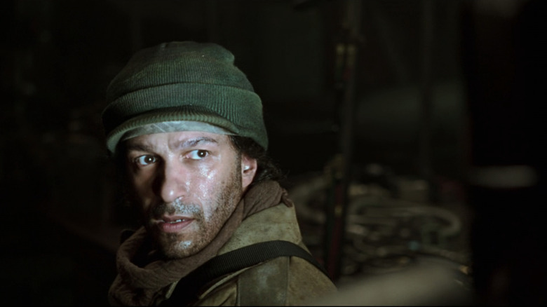 Tom Morello în timp ce un terorist se uită în sus în timp ce chipul lui este luminat de lumina albă în Iron Man