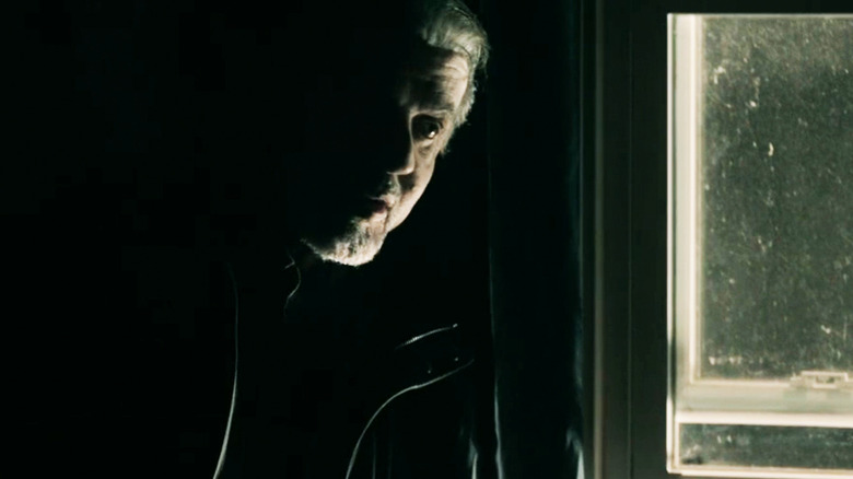 Sylvester Stallone ca agent Chester care stă lângă o fereastră în Alarum