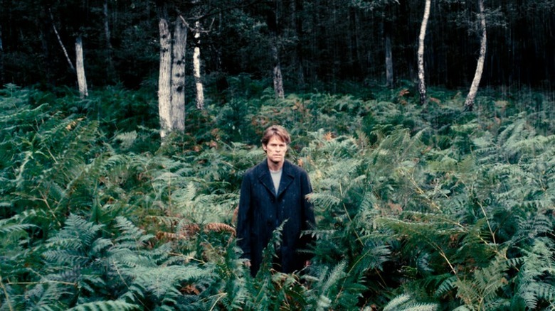 Personajul lui Willem Dafoe stând într -o pădure din Antichrist