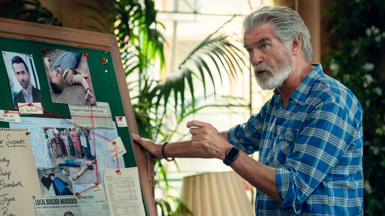 Ron Ritchie al lui Pierce Brosnan, ținându -se de un tablou de indicii în The Joi Murder Club