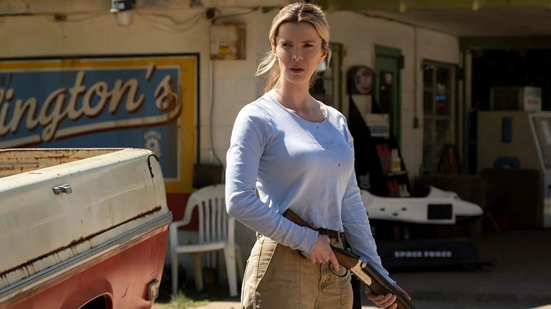 Crystal (Betty Gilpin) se află în fața unui magazin rustic de pe marginea drumului, lângă un camion murdar, cu o expresie serioasă în timp ce ținea o pușcă în vânătoare
