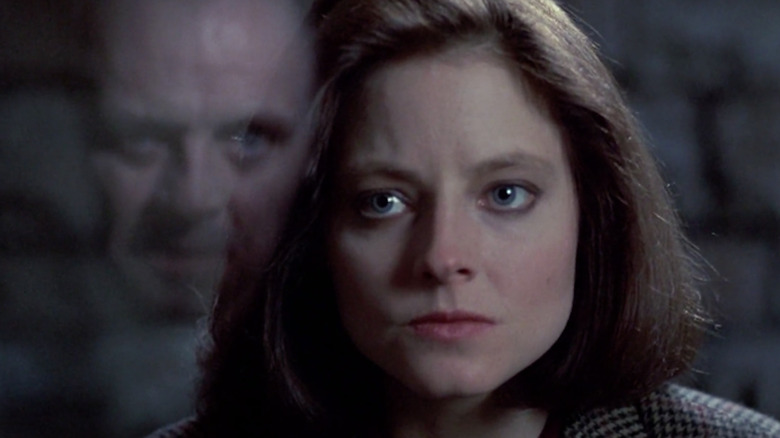 Jodie Foster în rolul lui Clarice Starling privindu -l pe Anthony Hopkins ca Hannibal Lecter, care este reflectat în paharul dintre ei, în The Silence of the Lambs