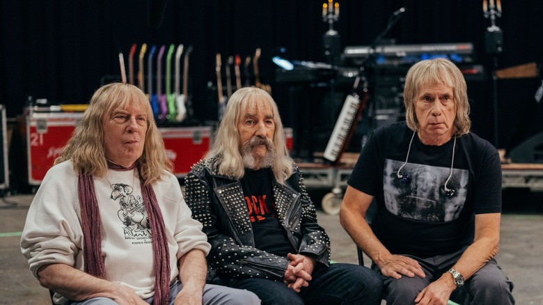 David St. Hubbins, Derek Smalls și Nigel Tuffnel stând pentru un interviu în Spinal Tap II: The End continuă