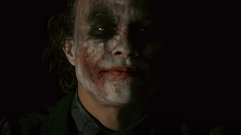 Heath Ledger în timp ce Jokerul stă în întuneric în The Dark Knight