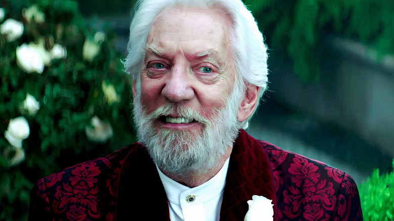 Zăpadă într -un costum de brocart roșu cu trandafirul alb pe rever în jocurile foamei