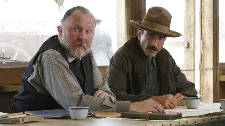 James Downey în rolul lui Al Rose, așezat lângă Daniel Day-Lewis, în rolul lui Daniel Plainview în acolo, va fi sânge