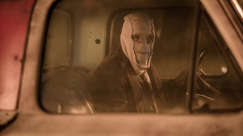 Bărbatul din mască stă într -un camion care se uită pe fereastră în străini: pradă noaptea