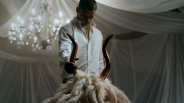 Cam Cade apucă un cap de mascot bizar al unei capre lângă corn în el