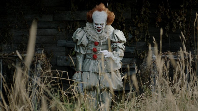 Pennywise stând în fața unei clădiri dărăpănate în ea
