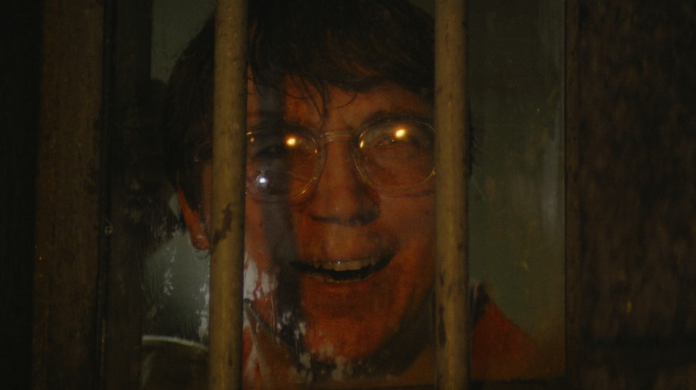 Paul Dano în rolul lui Riddler zâmbind în spatele gratiilor din Batman