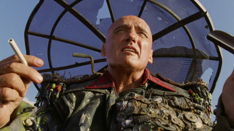 Dennis Hopper ca diacon care ține o țigară în Waterworld