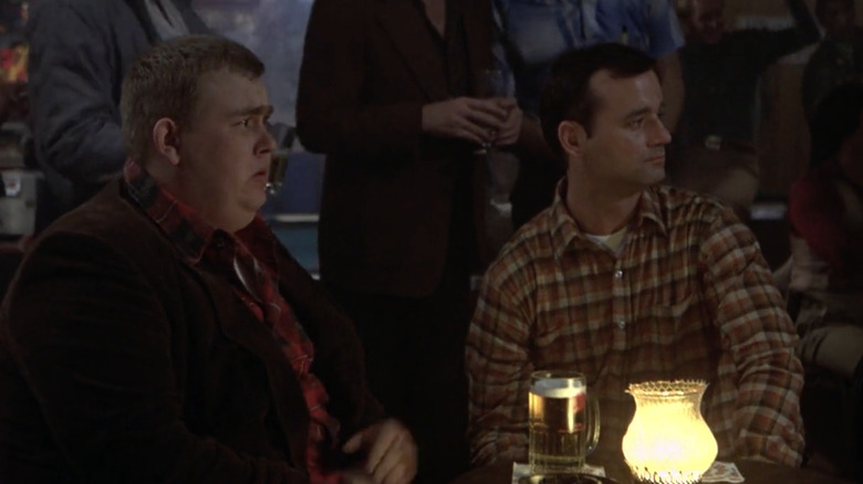 Bill Murray în timp ce John Winger împărtășește o masă de bar cu John Candy cu Dewey