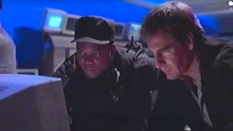 Alex Michaels de la Scott Bakula, arătând serios și privind un ecran al computerului din Netforce
