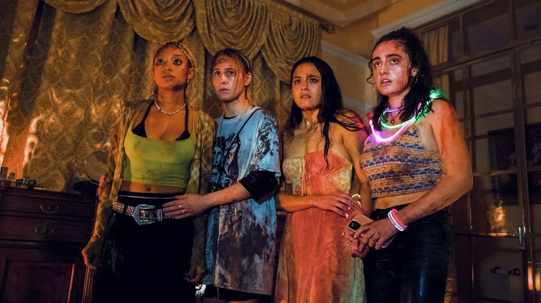 Sophie Bee Emma și Alice pline de sânge stând speriate în camera de zi în Bodies Bodies Bodies