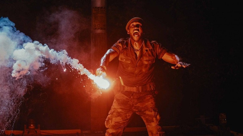 Mahershala Ali în rolul lui Kincaid care aprinde o rachetă în fața dinozaurului mutant în Jurassic World Rebirth