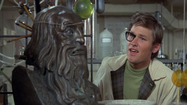 Dexter Riley poartă ochelari pe jumătate invizibili, uitându-se la un bust, în Now You See Him, Now You Don't