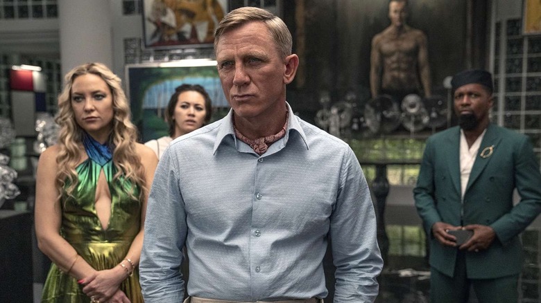 Benoit Blanc stând în fața lui Birdie Peg și Lionel în conacul lui Miles în Glass Onion: A Knives Out Mystery