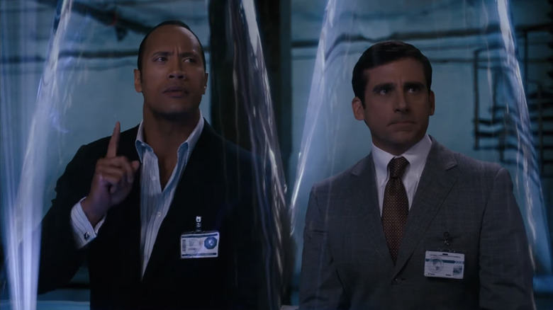 Dwayne Johnson în rolul Agentului 23 stă lângă Steve Carell în rolul lui Maxwell Smart în timp ce stau în conuri de tăcere în Get Smart