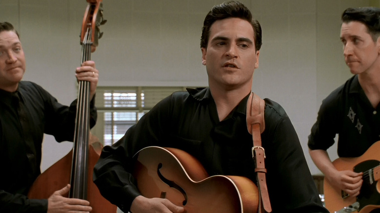 Johnny Cash cântând la chitară și cântând cu colegii de trupă în Walk the Line