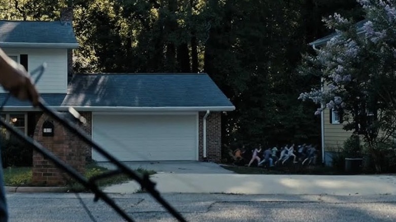 O mulțime de copii o urmăresc pe Gladys prin peluzele oamenilor în Weapons