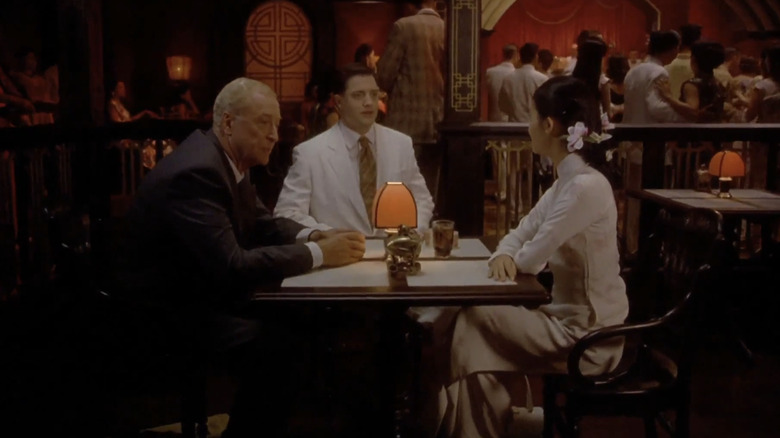 Thomas Fowler al lui Michael Caine, Alden Pyle al lui Brendan Fraser și Phuong al lui Do Thi Hai Yen stau în jurul unei mese la un restaurant din The Quiet American