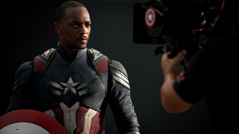 Anthony Mackie, în rolul lui Sam Wilson, s-a îmbrăcat și stând cu scutul în fața unei camere într-o imagine din culise din filmul Captain America: Brave New World
