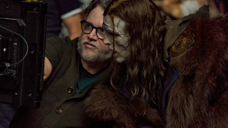 Regizorul Guillermo del Toro arată spre un ecran lângă Jacob Elordi în rolul monstrului dintr-o fotografie din culise de pe platoul lui Frankenstein