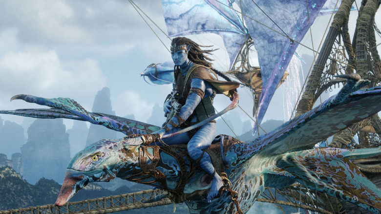 Jake Sully pe spatele unui dragon, cu nave cu pânze în spatele lui, în Avatar: Fire and Ash