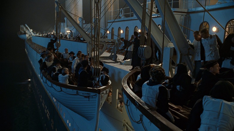 Mai mulți pasageri purtând veste de salvare se urcă în bărci de salvare în Titanic