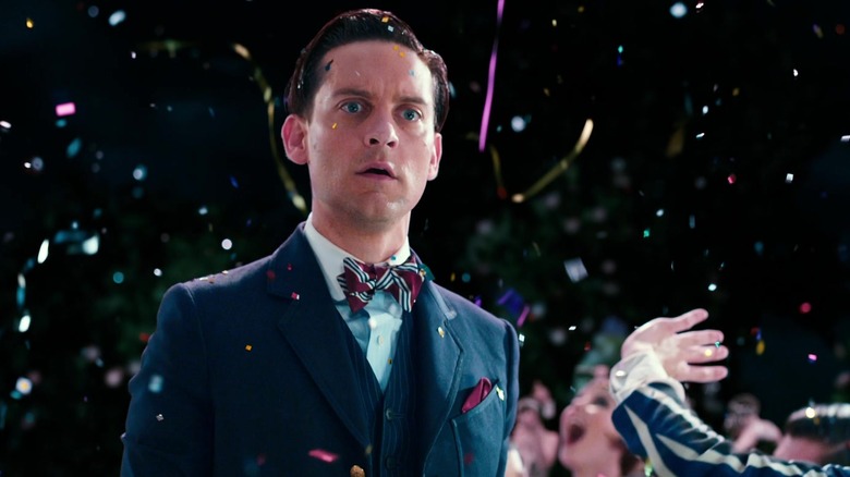 Nick Carraway de la Tobey Maguire pare îngrijorat în timp ce stă afară în timpul unui foc de artificii din Marele Gatsby