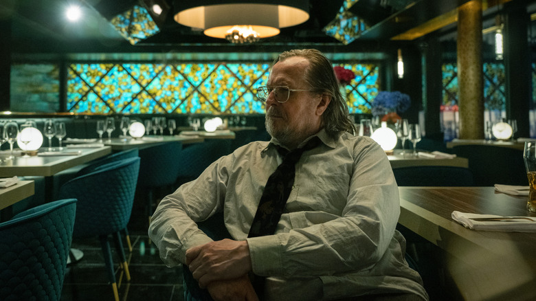 Jackson Lamb al lui Gary Oldman se uită în depărtare în timp ce stă într-un restaurant din Slow Horses